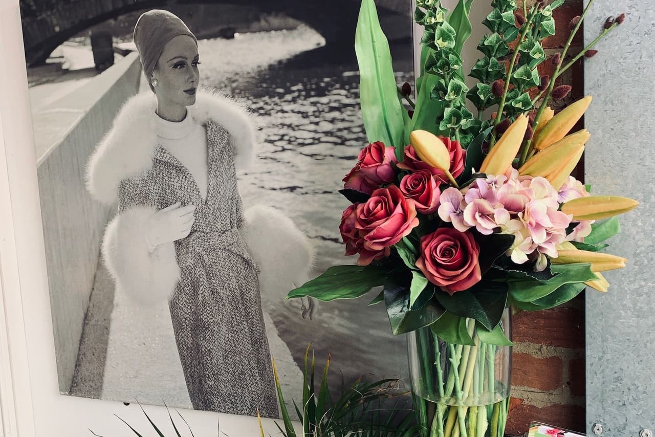 Framed vintage photo of a woman in a fur-trimmed coat beside a bouquet of roses and lilies