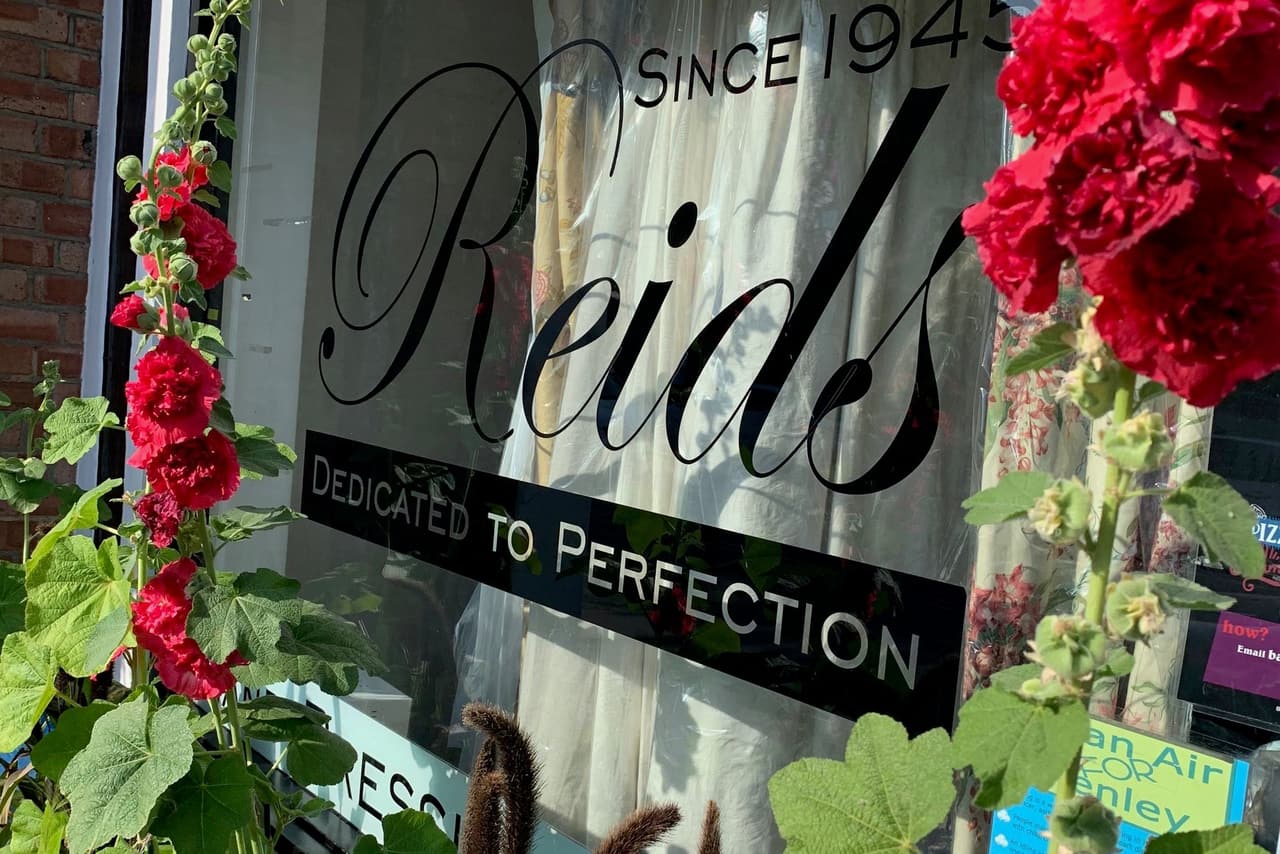 The Reids since 1945 sign, Dedicated to Perfection, framed by red roses