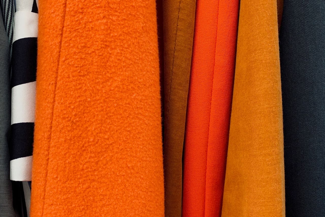 Orange and tangerine coats hanging side by side on a rail