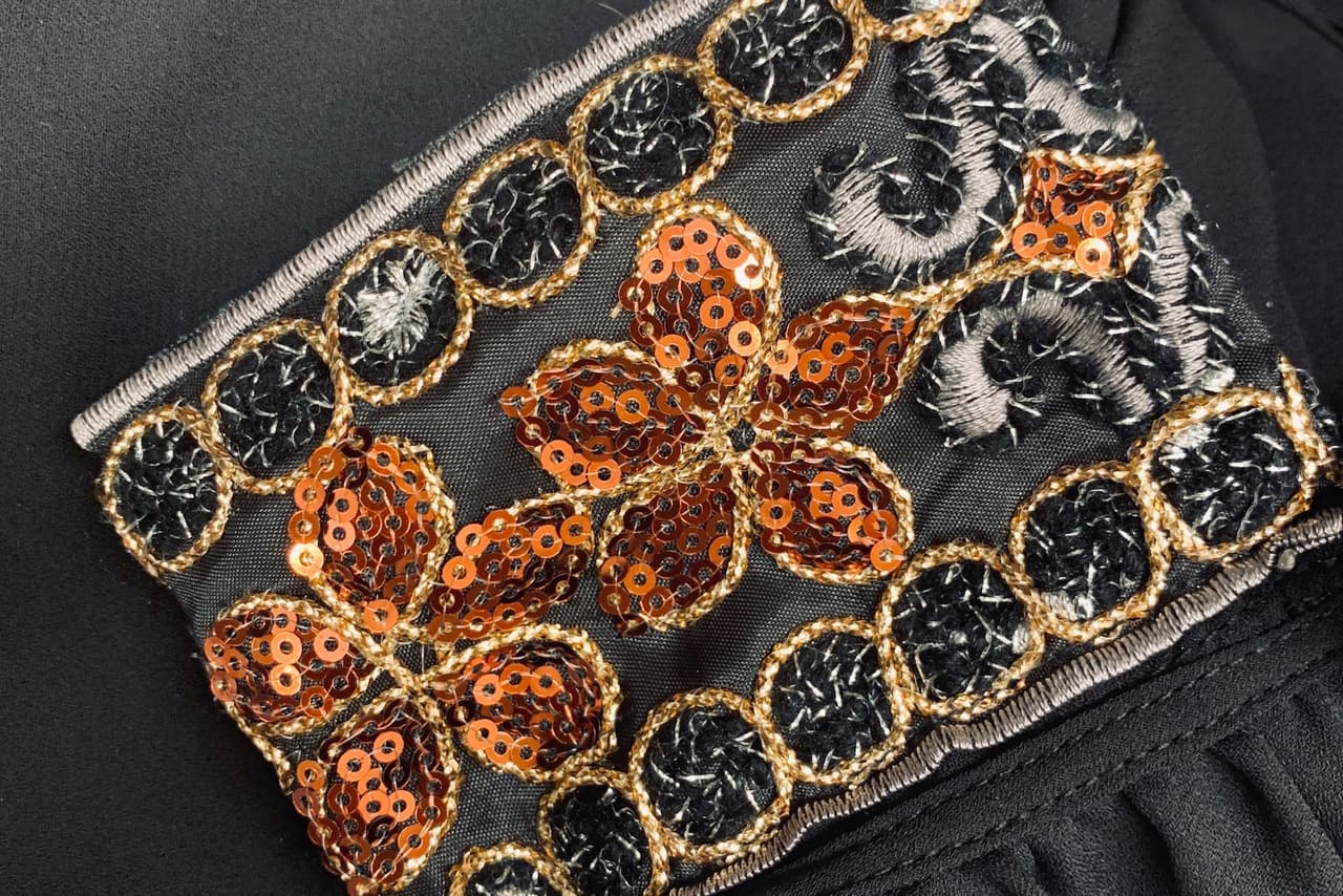 Close-up of copper sequin and gold embroidery on a black garment